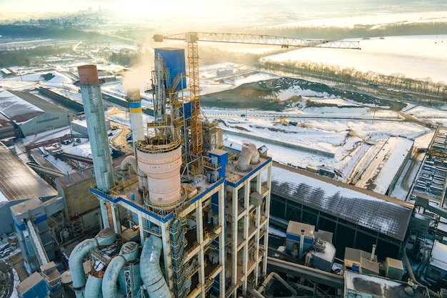 Vista aérea da fábrica de cimento com alta estrutura fabril e guindaste de torre na área de produção industrial.