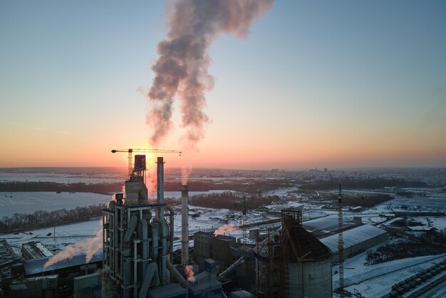 Vista aérea da fábrica de cimento com estrutura de planta de concreto alto e guindaste de torre na área de produção industrial à noite Fabricação e conceito de indústria global