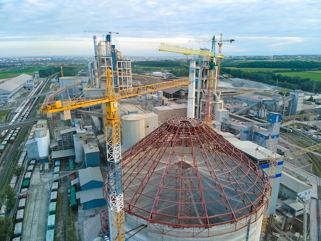 Vista aérea da fábrica de cimento em construção com alta estrutura de planta de concreto e guindastes de torre na área de produção industrial. Fabricação e conceito de indústria global.