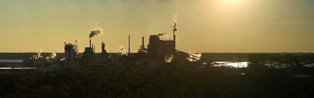 Vista aérea da grande fábrica com chaminé do processo de produção poluindo a atmosfera no estaleiro de fabricação da planta Local industrial ao pôr do sol