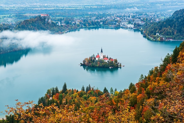 Vista aérea da Igreja da Assunção no Lago Bled, Eslovênia, no aurumn com árvores coloridas