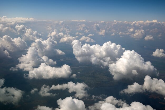 Vista aérea da janela do avião de nuvens brancas e fofas em um dia ensolarado.