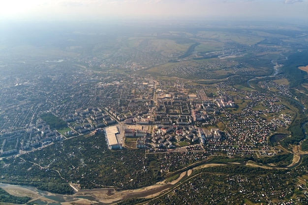 Vista aérea da janela do avião em alta altitude da terra coberta com fina camada branca de neblina e nuvens distantes ao pôr do sol