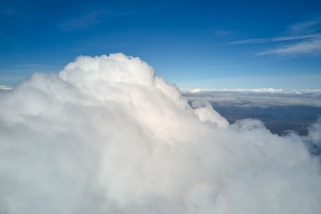 Vista aérea da janela do avião em alta altitude da terra coberta de nuvens cumulus brancas e inchadas