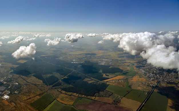 Vista aérea da janela do avião em alta altitude da terra coberta por nuvens cúmulos brancas inchadas.