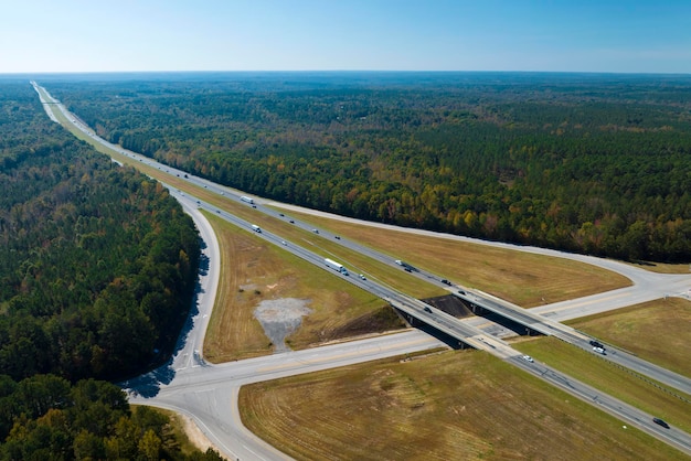 Vista aérea da junção de viaduto de auto-estrada com carros e caminhões de tráfego rápido na área rural americana Infraestrutura de transporte interestadual nos EUA