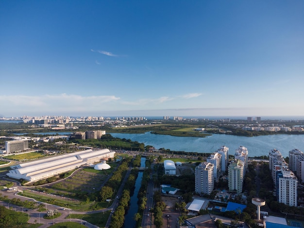 Vista aérea da lagoa de Jacarépaguá no Rio de Janeiro, Brasil. Edifícios residenciais e montanhas ao redor do lago. Praia da Barra da Tijuca ao fundo. Dia ensolarado. Pôr do sol. Foto de drone.