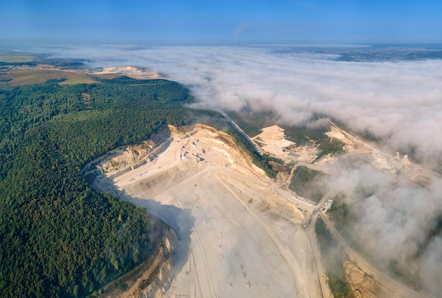 Vista aérea da mineração a céu aberto de materiais calcários para a indústria da construção com escavadeiras e caminhões basculantes