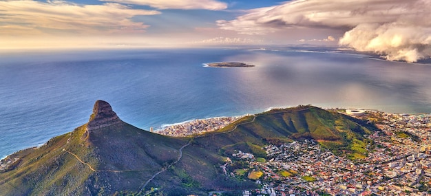Vista aérea da montanha Lions Head com o oceano e céu nublado cópia espaço Bela paisagem de montanhas verdes com muita vegetação ao redor de uma cidade urbana na Cidade do Cabo, África do Sul
