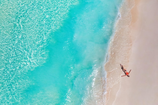 Vista aérea da mulher na praia nas ilhas Maldivas. Férias e aventura. Viajar ondas turquesas