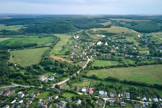 Vista aérea da paisagem de campos agrícolas cultivados verdes com culturas em crescimento e casas de aldeias distantes