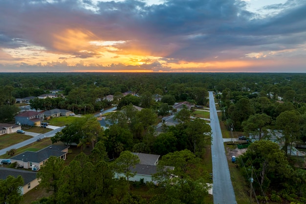 Vista aérea da paisagem de casas particulares suburbanas entre palmeiras verdes na área rural tranquila da Flórida ao pôr do sol