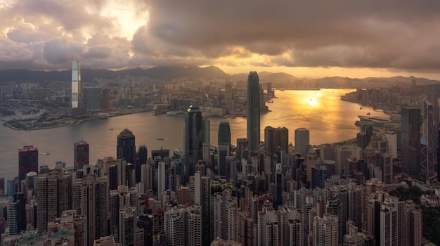 Vista aérea da paisagem urbana ao lado do rio contra o céu nublado durante o pôr-do-sol