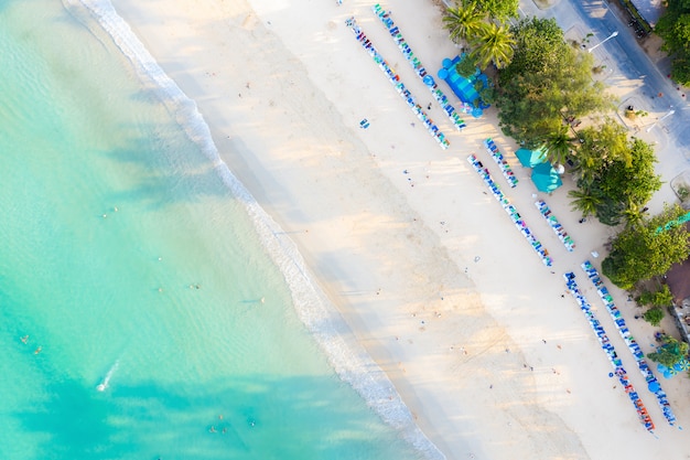 Vista aérea da praia arenosa com os turistas que nadam na água do mar clara bonita em Phuket, Tailândia.
