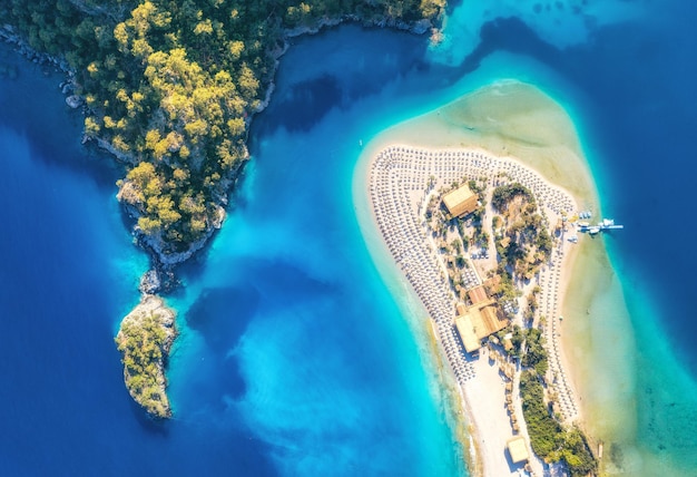 Vista aérea da praia com guarda-chuvas verdes árvores montanha ao pôr do sol no verão Lagoa azul em Oludeniz Turquia Paisagem tropical com mar baía ilha banco de areia branca água azul vista superior