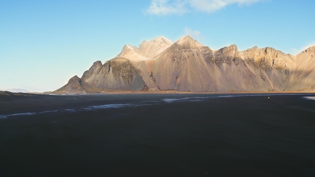 Vista aérea da praia de areia de Stokksnes em um cenário islandês, majestosas montanhas vestrahorn em uma paisagem ártica. Uma vista panorâmica espetacular da Islândia com a costa do oceano Atlântico, o litoral. Movimento lento.