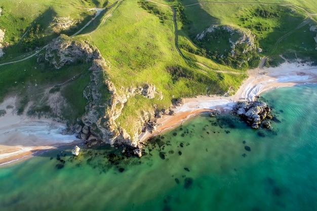 Vista aérea da praia Grandes colinas ao redor Dia ensolarado ao amanhecer Mar esverdeado Drone Photo