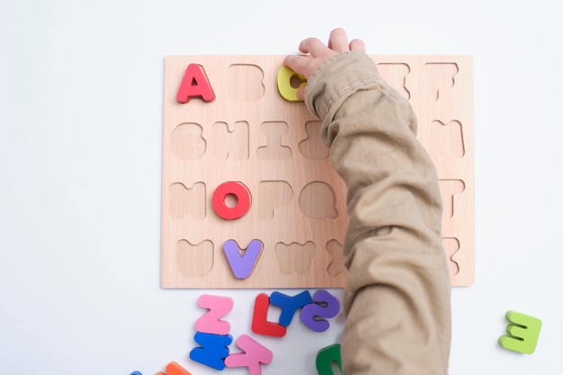 Vista aérea da pré-escola, menino do jardim de infância brincando com blocos de alfabeto, crianças aprendendo inglês com quebra-cabeça educacional de madeira do brinquedo abc