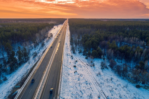 Vista aérea da rodovia reta e pinhal no inverno ao pôr do sol. Vista de cima