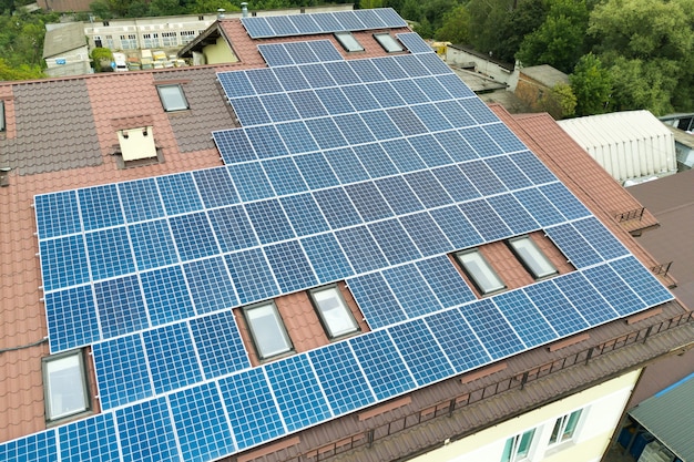 Vista aérea da usina solar com painéis fotovoltaicos azuis montados no telhado do prédio de apartamentos.