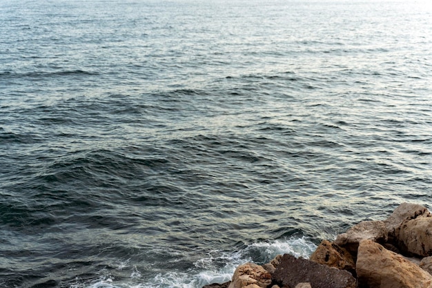 Vista aérea das ondas do mar quebrando nas rochas perto do penhasco