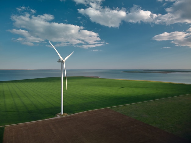 Vista aérea das turbinas eólicas e do campo agrícola perto do mar ao pôr do sol