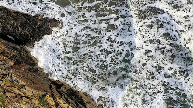 Vista aérea de belas ondas do oceano contra uma paisagem de penhasco acidentado