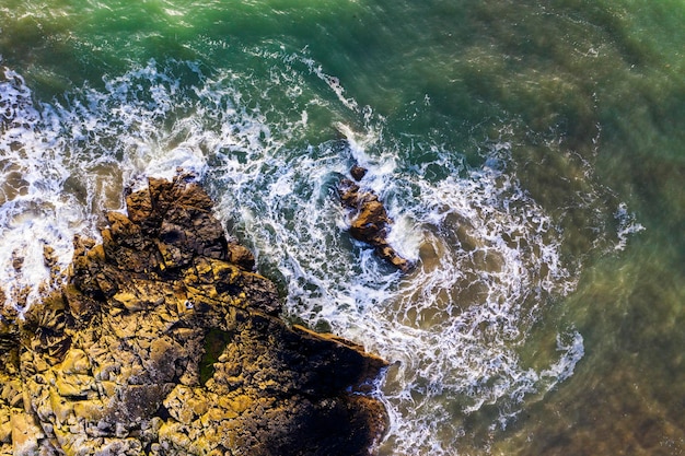 Vista aérea de belas ondas oceânicas quebrando contra rochas ásperas