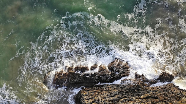Vista aérea de belas ondas oceânicas quebrando contra rochas ásperas