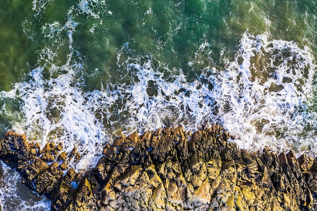 Vista aérea de belas ondas oceânicas quebrando contra rochas ásperas