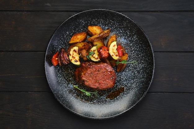 Vista aérea de bife com fatias de batata e legumes grelhados