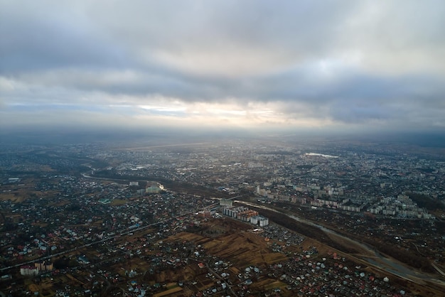 Vista aérea de casas rurais e prédios de apartamentos distantes na área residencial da cidade durante o tempo nublado.