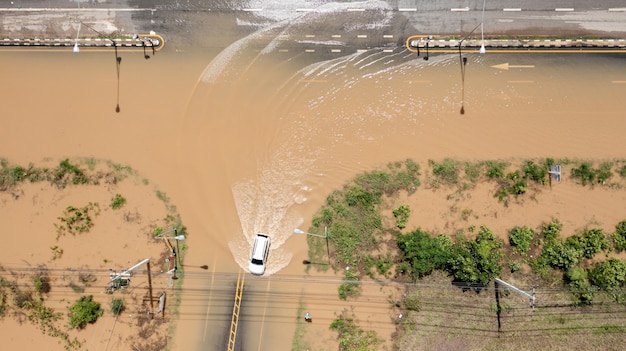 Vista aérea de cima da aldeia inundada e estrada secundária com carro, vista de cima filmada por drone