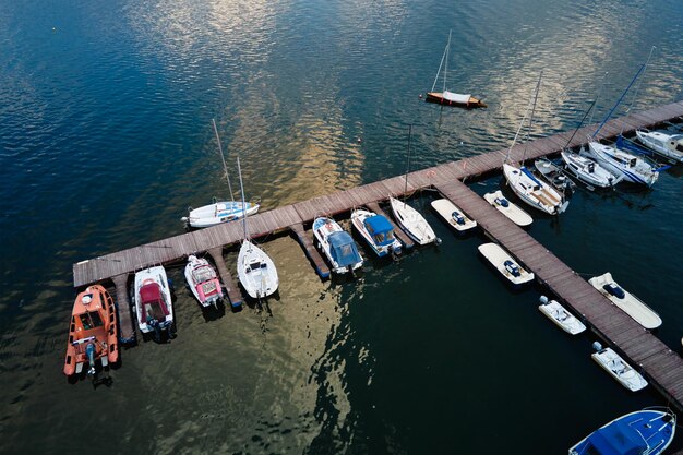 Vista aérea de cima de barcos e pequenos jachts perto do cais de madeira no lago de entretenimento de verão na água