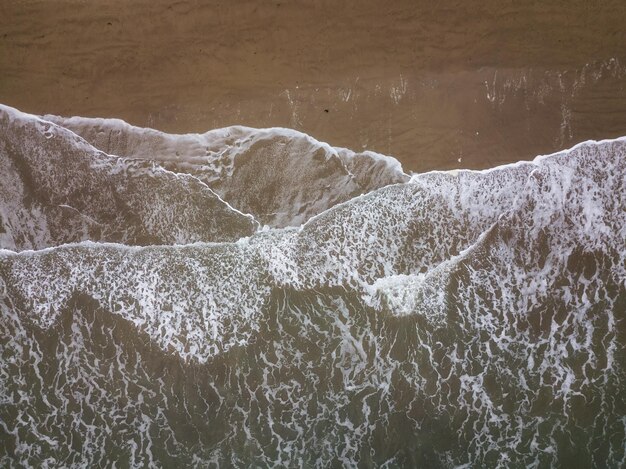 Vista aérea de cima de uma praia de areia com ondas quebrando