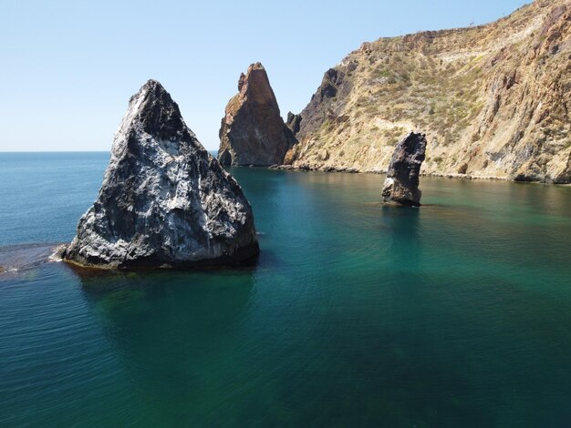 Vista aérea de cima no calmo mar azul e costas rochosas vulcânicas pequenas ondas na superfície da água em