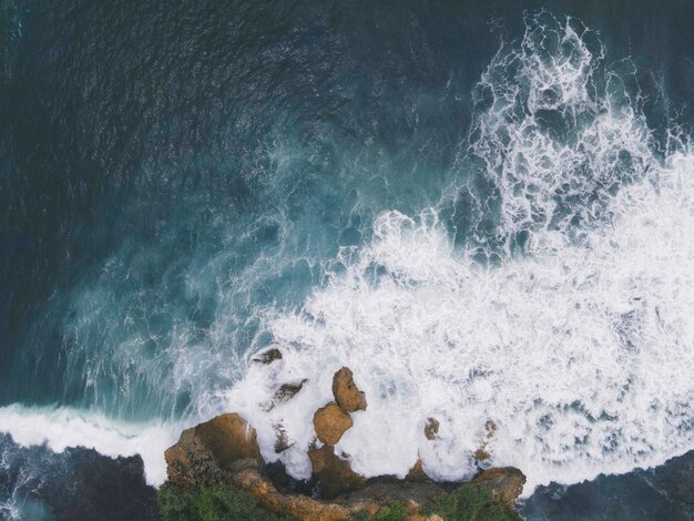 Vista aérea de cima para baixo de ondas gigantes do oceano batendo e espumando na praia de coral