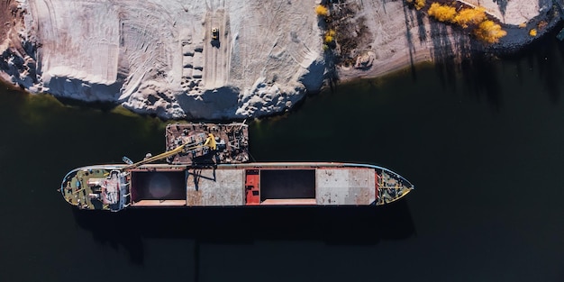 Vista aérea de cima para baixo do carregamento de navio de carga seca As barcaças do rio são preenchidas com materiais de construção a granel