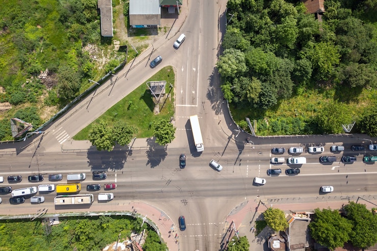 Foto vista aérea de cima para baixo do cruzamento de uma rua movimentada com tráfego de carros em movimento.