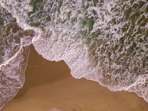 Vista aérea de cima para baixo em uma praia de areia com ninguém surfando no mar