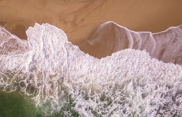 Vista aérea de cima para baixo em uma praia de areia com ninguém surfando no mar