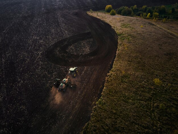 Vista aérea de dois modernos tratores verdes arando campos agrícolas secos e semeando preparando a terra para a sementeira de primavera