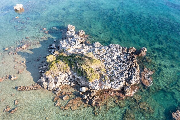 Vista aérea de drones de formações rochosas com musgo no mar Egeu azul