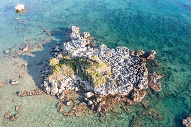 Foto vista aérea de drones de formações rochosas com musgo no mar egeu azul