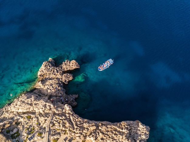 Vista aérea de falésias pelo mar azul com barco