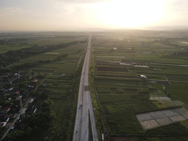 Vista aérea de Jalan Raya Indonésia com poucos carros e vista do nascer do sol