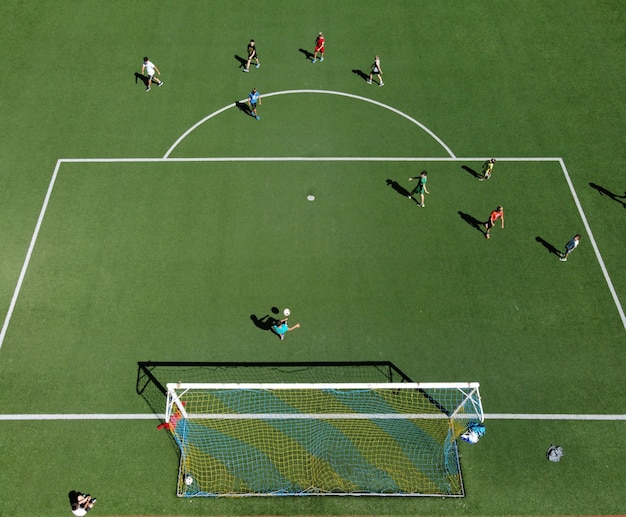 Vista aérea de jogadores de futebol em um campo de esportes jogando uma partida de futebol