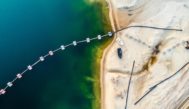 Vista aérea de máquinas e equipamentos de mina perto de um lago azul profundo na superfície arenosa