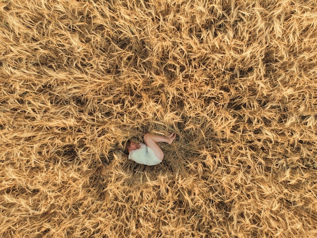 Vista aérea de mulher deitada em um campo de trigo