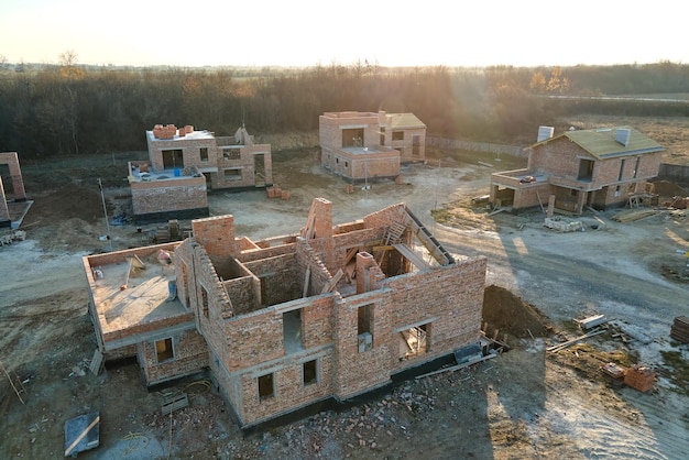 Vista aérea de novas casas com paredes de estrutura de tijolo em construção na área rural suburbana Desenvolvimento de imóveis nos subúrbios da cidade moderna